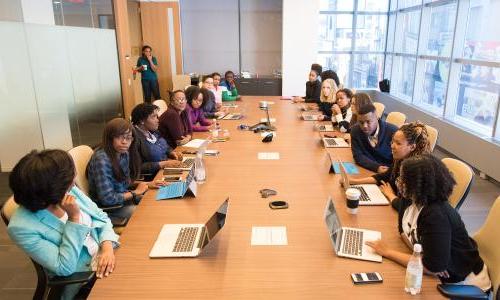 Many people sit around a table in a meeting room.